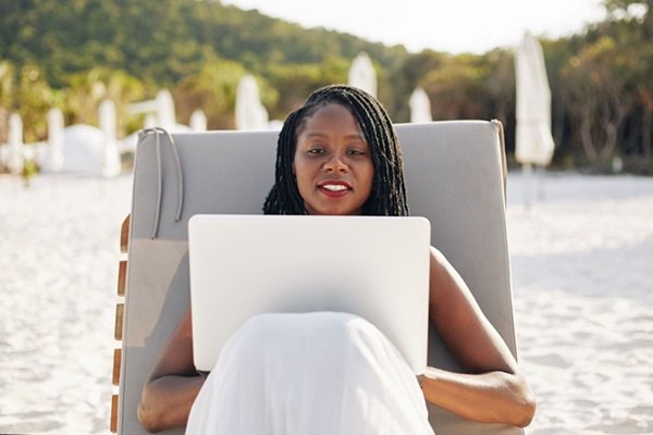 Woman using a laptop while relaxing at the beach
