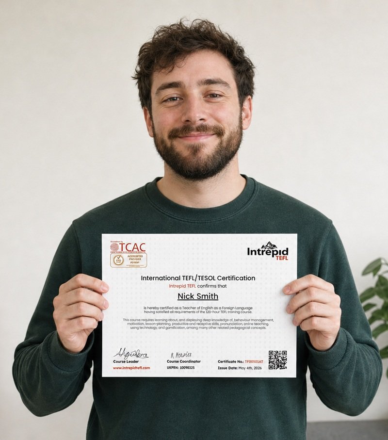 Real Intrepid TEFL student holding his IntrepidTEFL 120-hour TEFL certificate smiling with pride