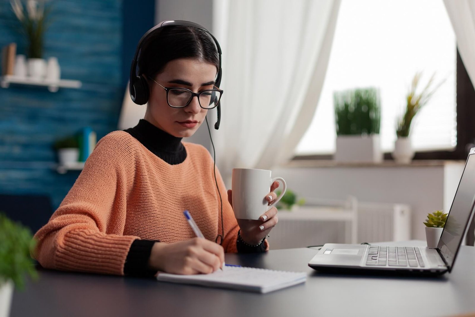 Adult taking notes while studying an online course