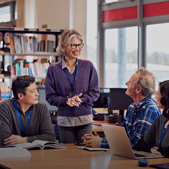 Older woman teaching adults in a library